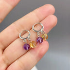 Hand holding natural amethyst and citrine S925 silver earrings fingers close-up, Crystalvana