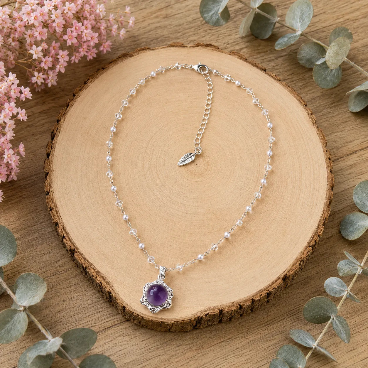 Model smiling wearing amethyst pendant necklace hand on hair, Crystalvana